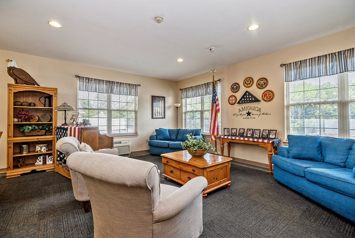 A cozy living room with comfortable seating and decorations, featuring two sofas, a coffee table, and an American flag.