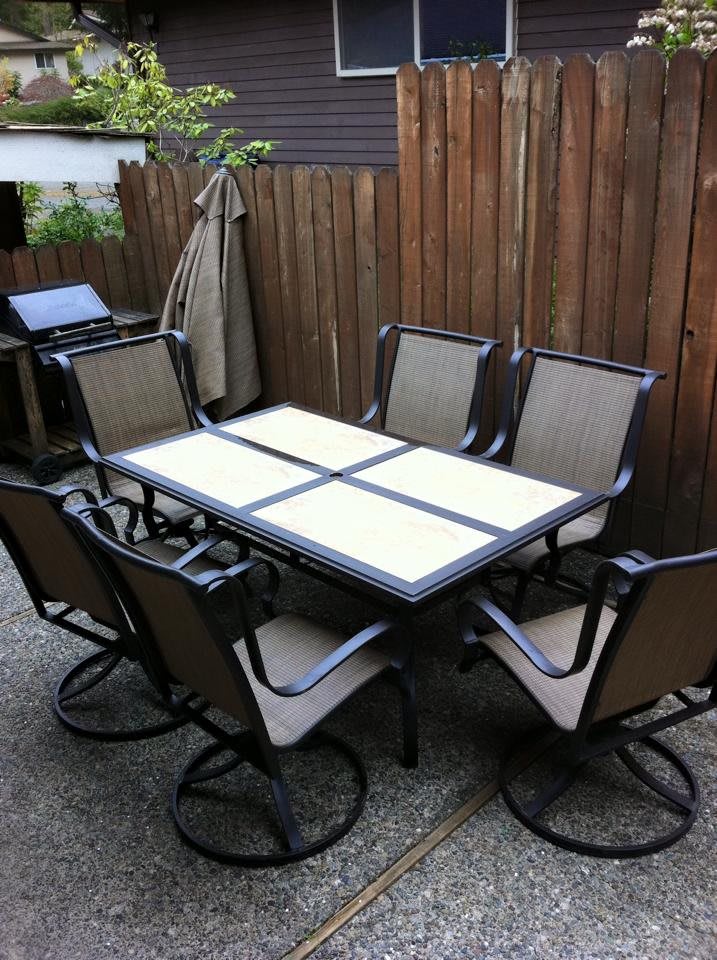 A set of outdoor patio furniture with a table and six chairs arranged neatly.