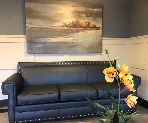 A stylish interior featuring a sleek black sofa, elegant wall art, and vibrant flowers.
