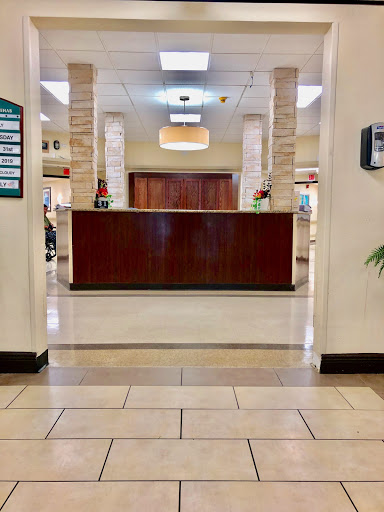 A view of a reception area within a healthcare facility, featuring a wooden reception desk and tiled floors.