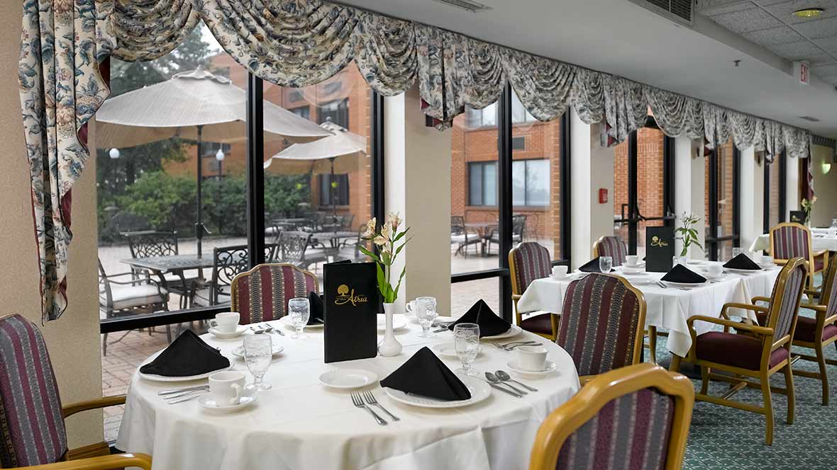 An elegantly set dining table in a restaurant with a view of the outdoor patio.