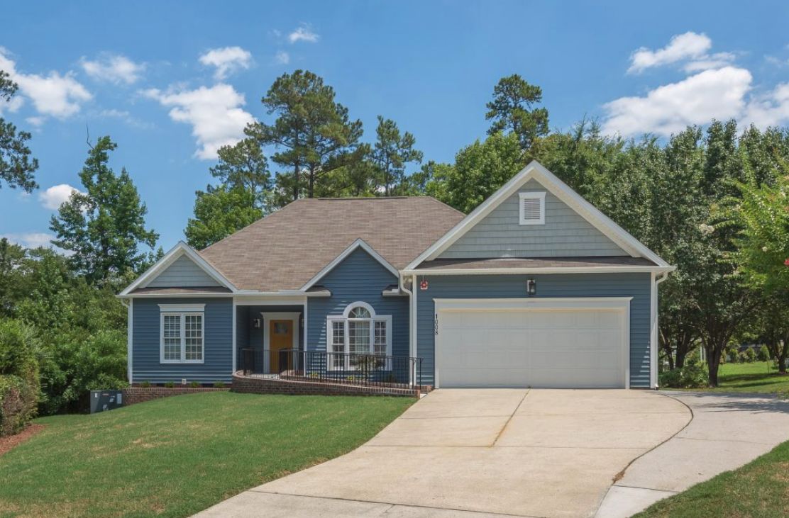 A suburban house with a blue exterior, garage, and a well-maintained yard.