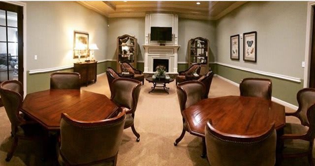 A luxurious living room with elegant leather chairs and a central fireplace.