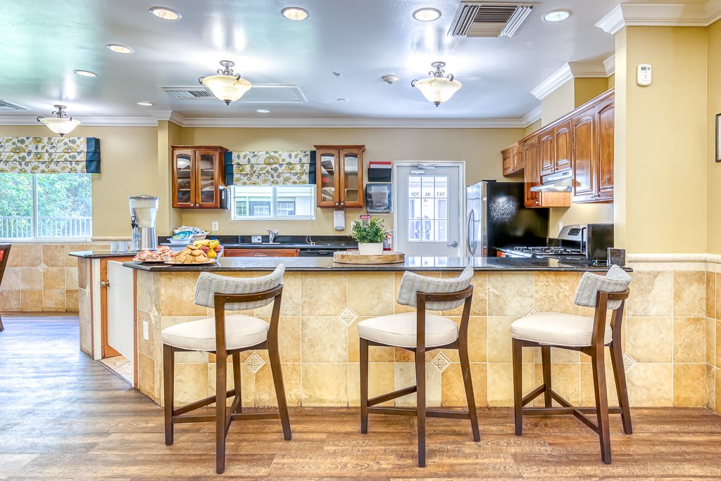 A modern kitchen interior featuring bar stools at a large countertop with wooden flooring.