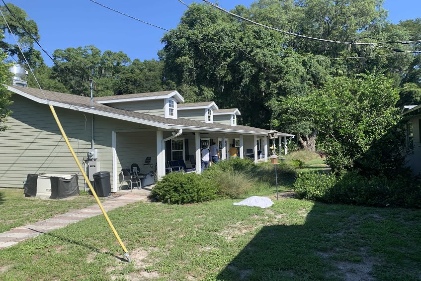 A sunny day at a house with a spacious front yard and surrounding trees.
