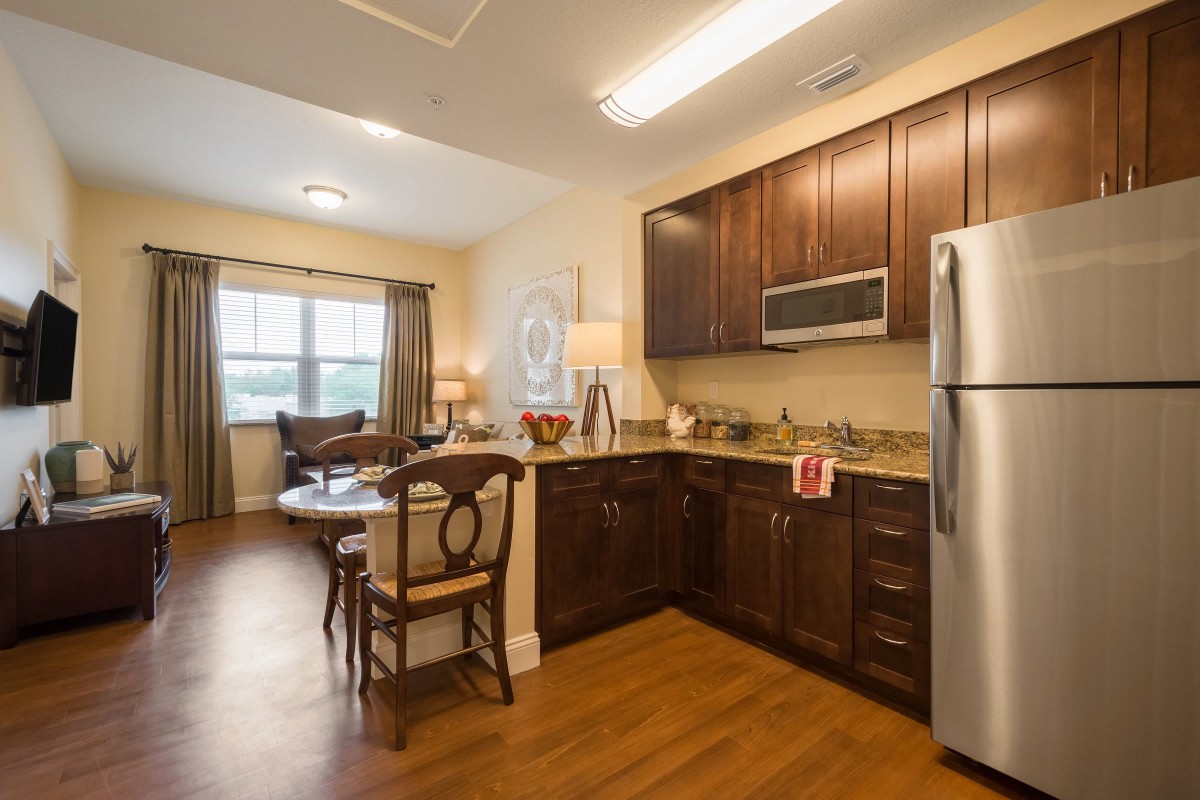 A modern apartment featuring an open-concept kitchen and dining area with wood flooring and stainless steel appliances.