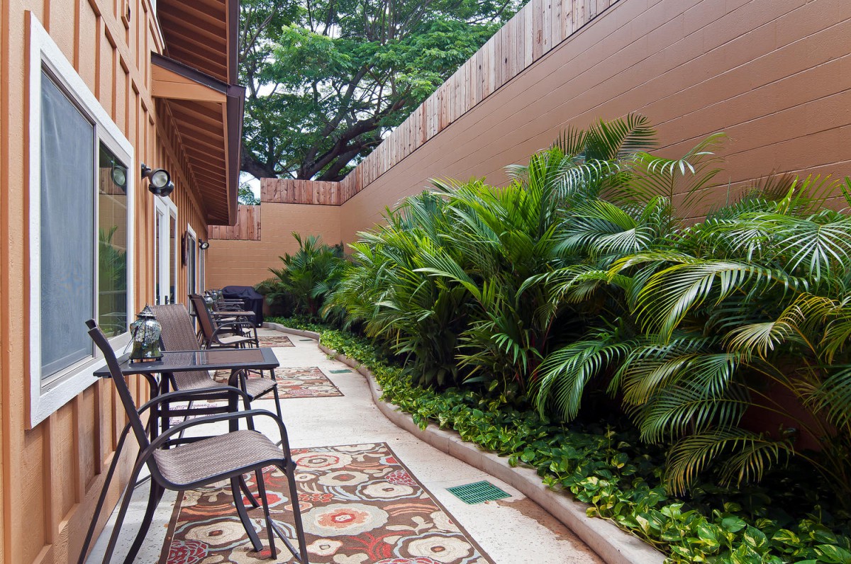 A cozy outdoor patio area with chairs and tables surrounded by lush greenery.