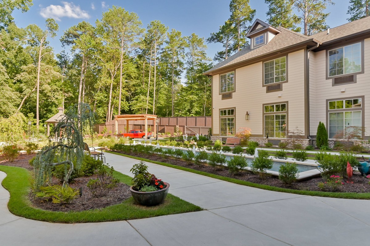 A modern house with a landscaped garden and driveway surrounded by trees.