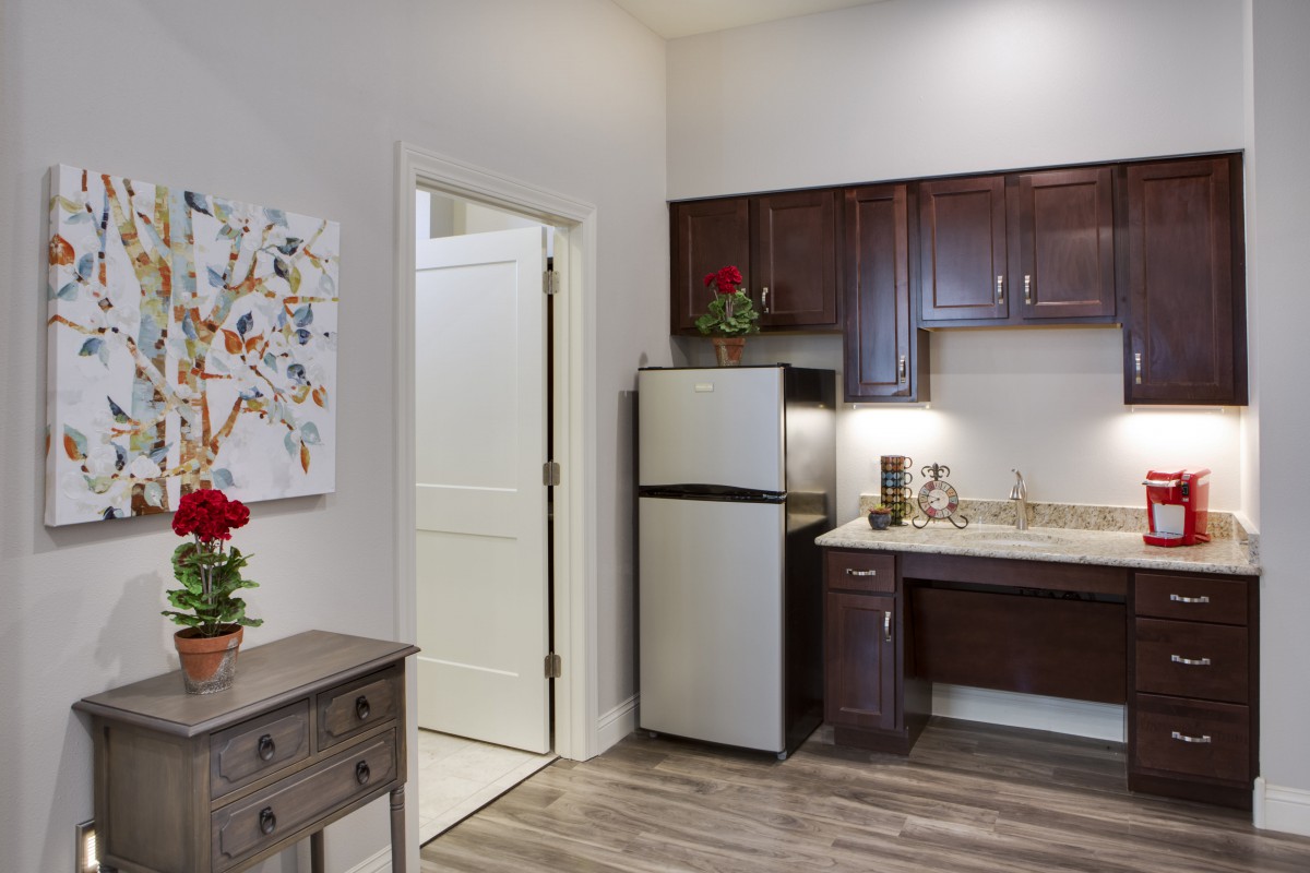 A modern kitchen with dark wood cabinets and a compact fridge in an apartment setting.