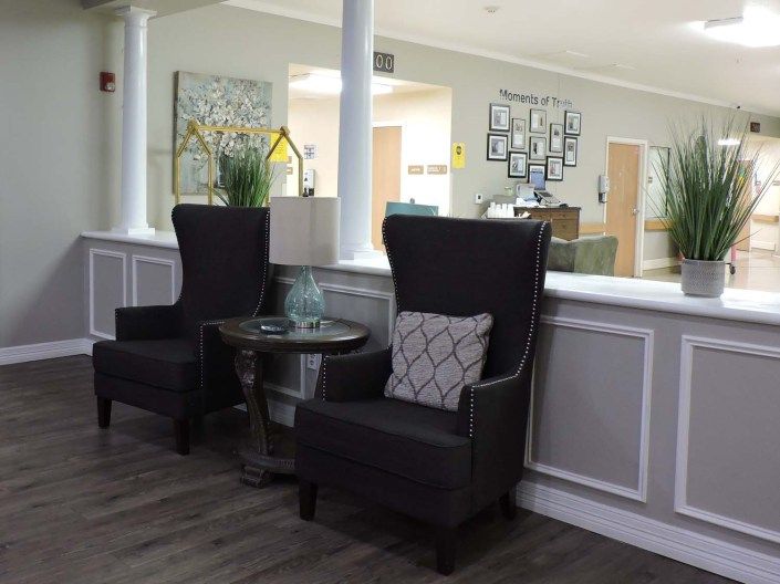 A modern lobby seating area with two dark armchairs, a small table, and decorative elements.