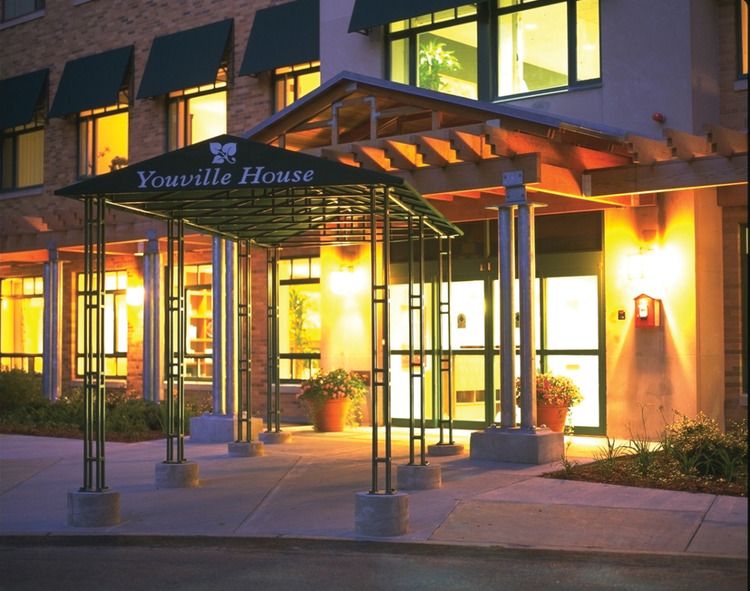 The illuminated entrance of a hotel under an awning at night.