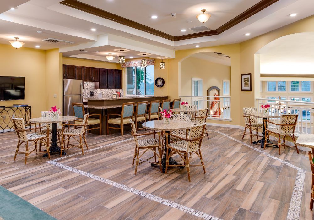 A modern kitchen and dining area featuring wooden flooring, tables, and a bar counter.