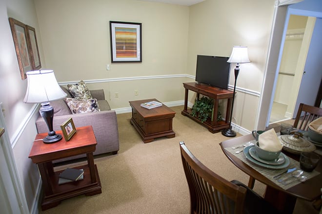 A cozy living room with a sofa, coffee table, TV, and floor lamp.