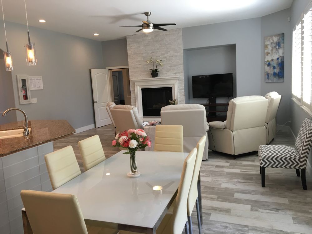 A modern living room with a dining area featuring a fireplace, comfortable seating, and a television.