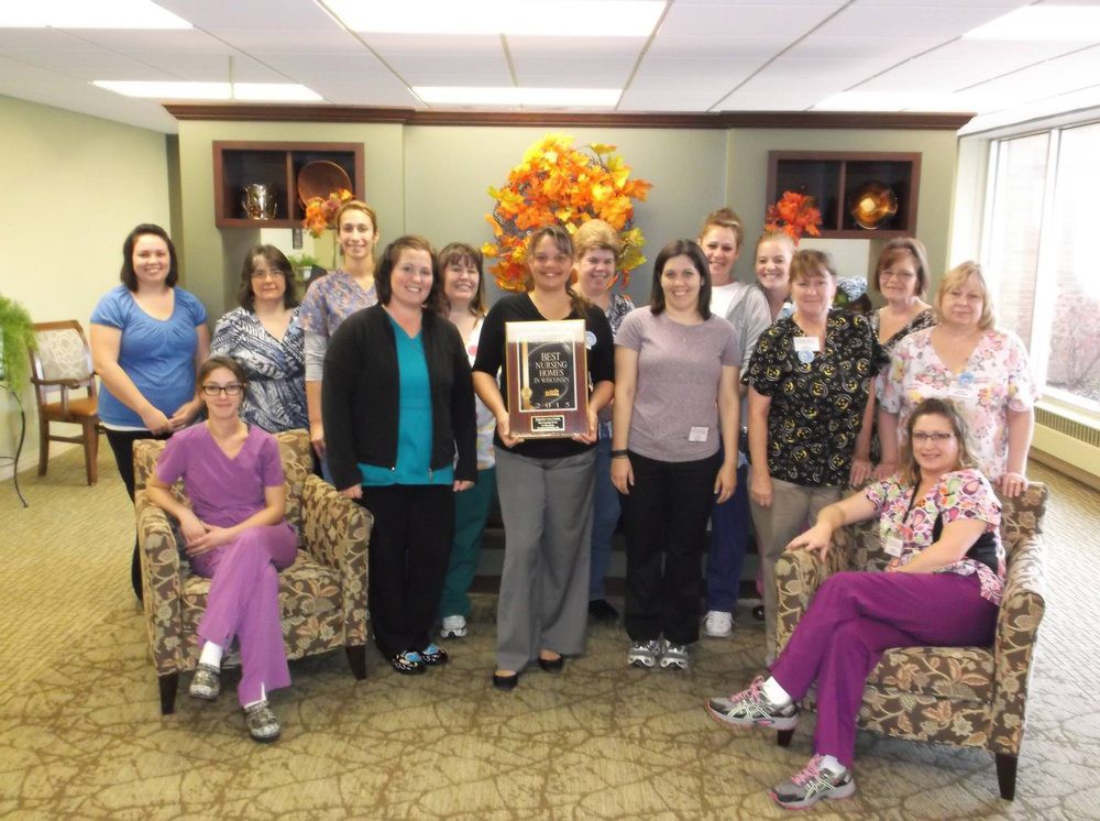 A team poses together in an office setting, holding an award.