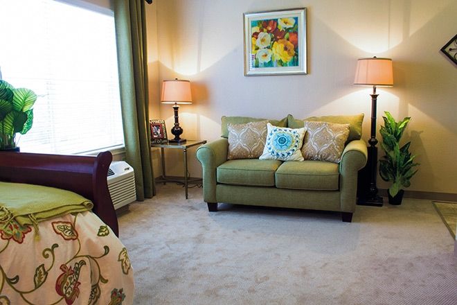 A cozy living room with a green sofa, decorative pillows, and warm lighting from table lamps.