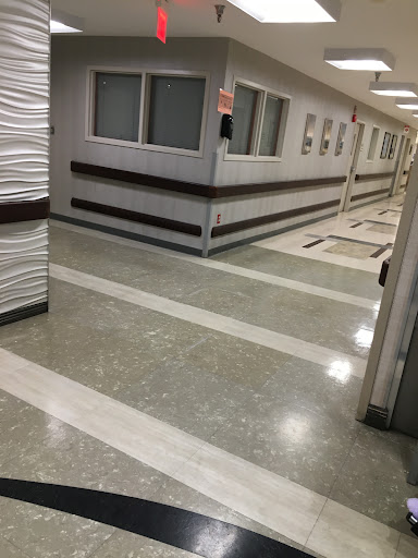 A view of a modern hospital corridor featuring clean lines and a polished floor.