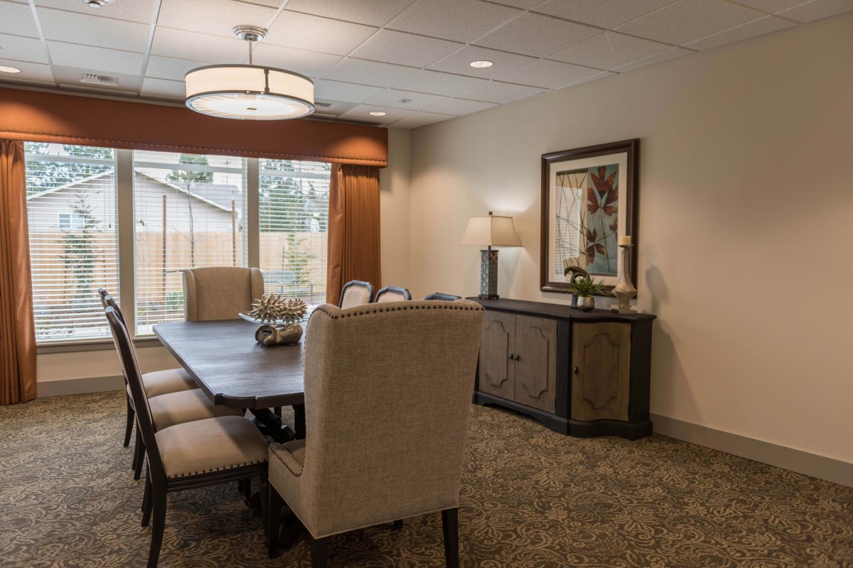 A well-decorated dining room with a large table, upholstered chairs, a sideboard, and elegant lighting.