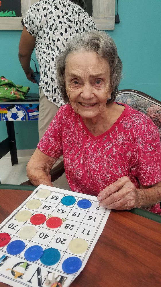 An elderly woman smiling while playing bingo indoors.