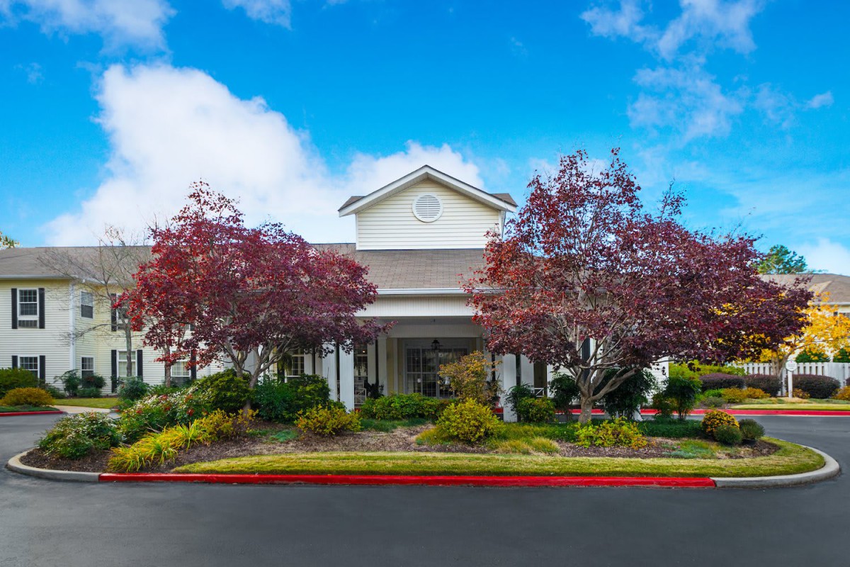 A picturesque view of a building surrounded by trees and greenery under a clear blue sky.