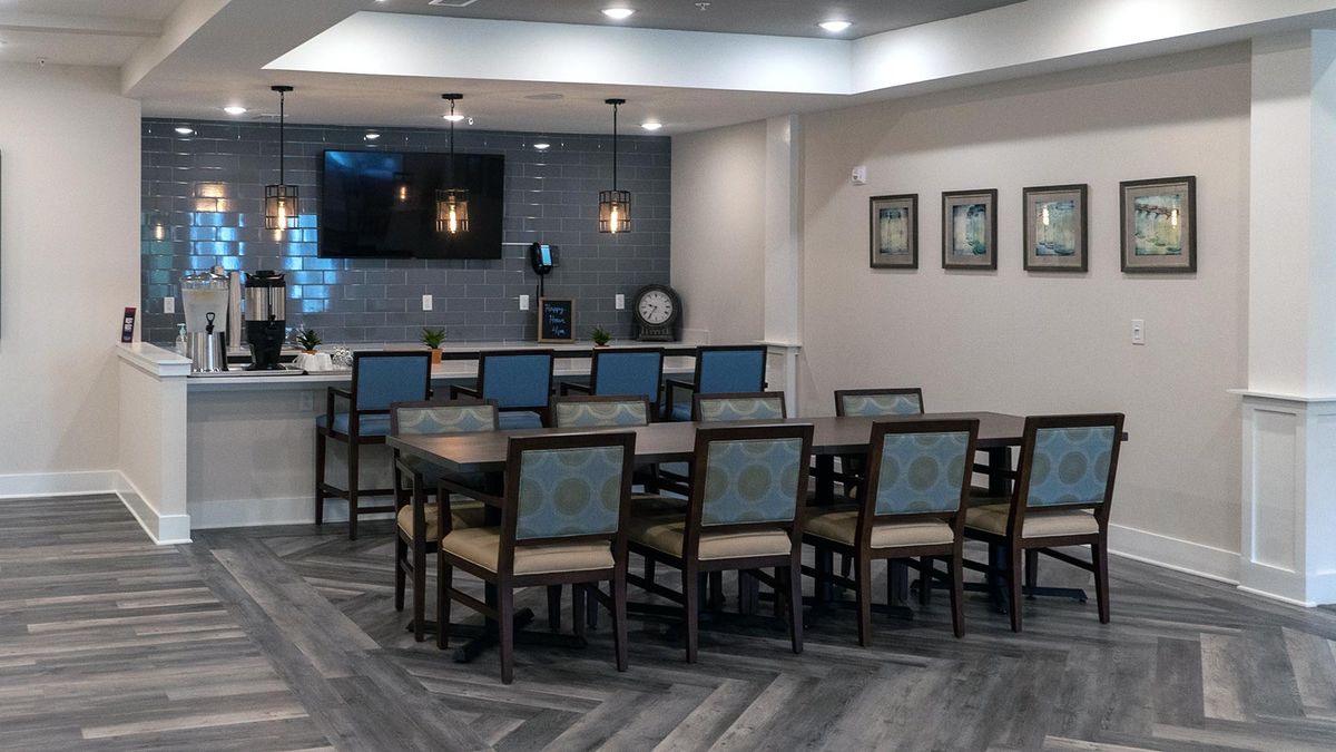 A modern dining or conference area with multiple chairs, a TV on the wall, and stylish lighting.