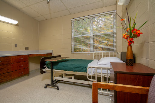 A clean and minimalist hospital patient room equipped with a bed, bedside table, and natural light from the window.