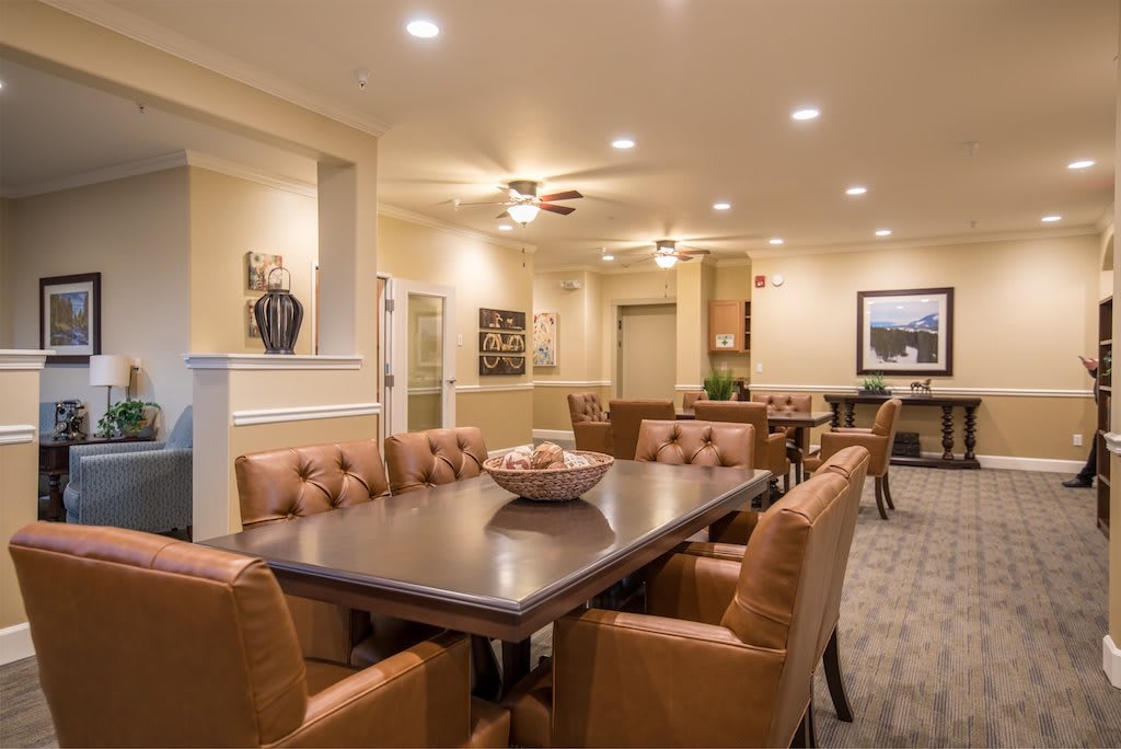 A well-lit dining area featuring a large table surrounded by comfortable chairs and elegant decor.
