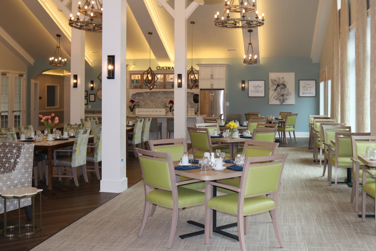 A modern dining area with elegant chandeliers, featuring neatly arranged tables and chairs.