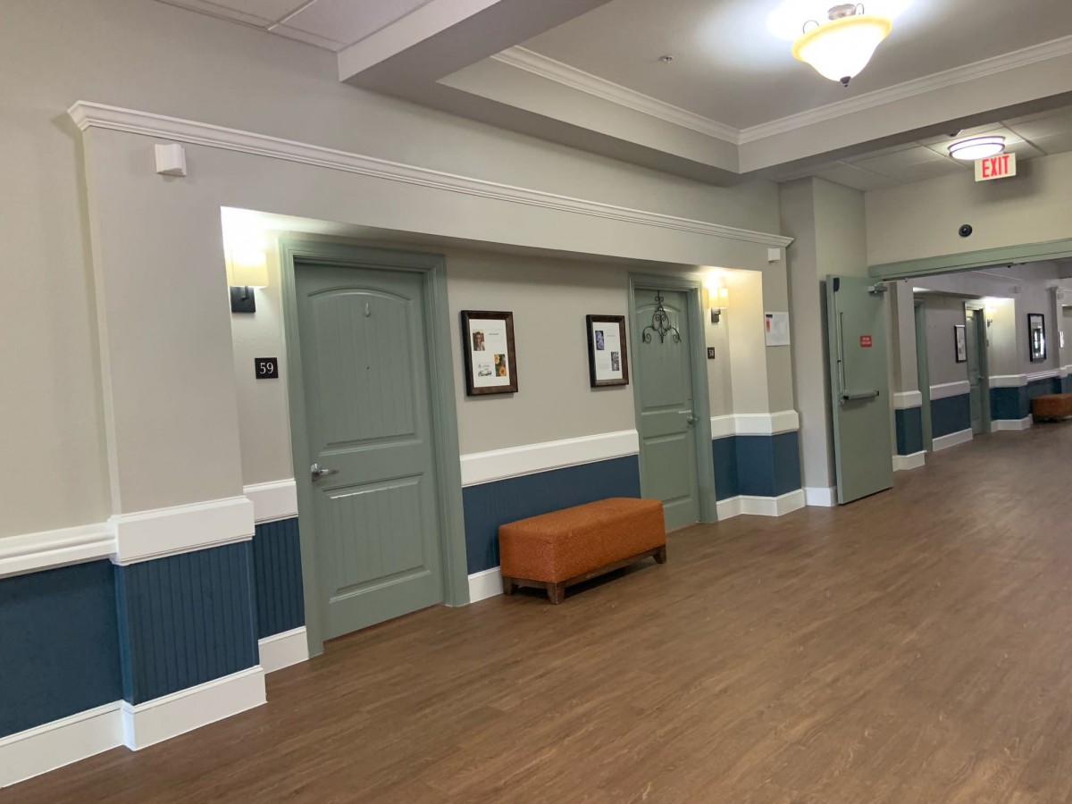 A well-lit hallway with multiple doors and a bench along the wall.