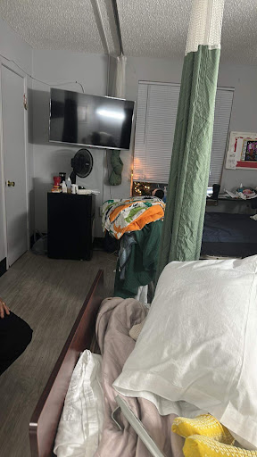 A cozy bedroom setup featuring a television and various items on the bed.