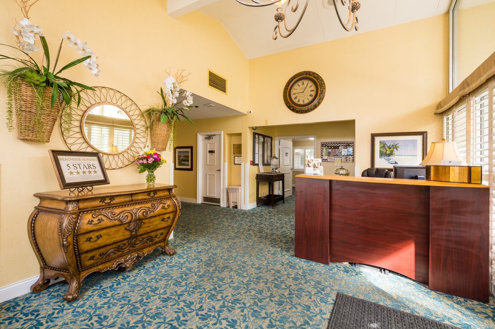 A warmly decorated lobby area featuring a wooden reception desk, patterned carpet, and elegant mirrors.