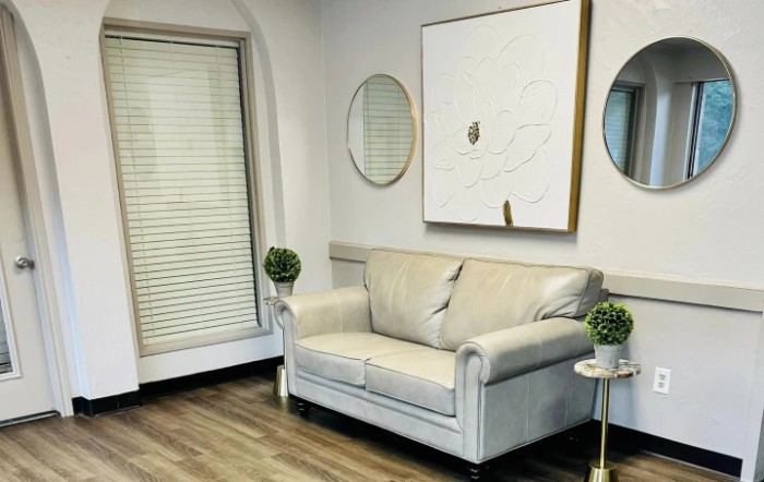 A modern living room with a white couch, decorative mirrors, and minimalist artwork.