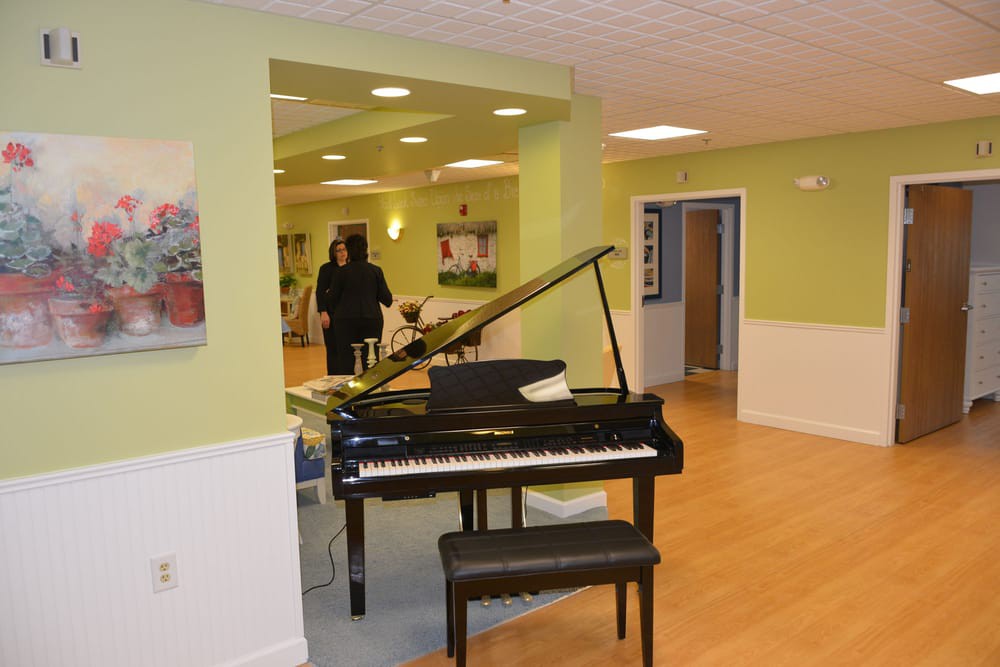 A spacious room with a black grand piano and green walls, featuring modern decor.