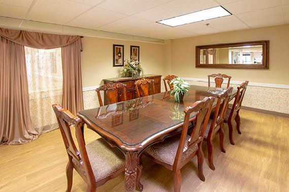 A well-appointed dining room featuring a polished wooden table and chairs, complemented by elegant decor and a large mirror.