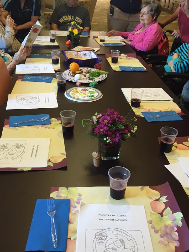 A meeting table set with documents and drinks, surrounded by attendees.