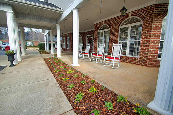 A cozy brick porch with rocking chairs and elegant landscaping.
