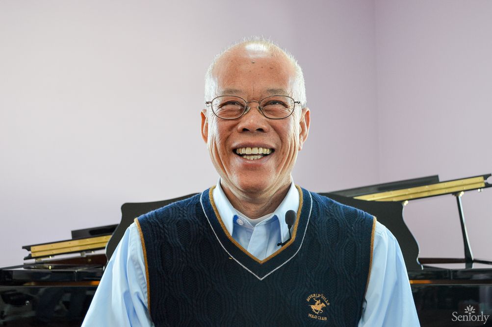A smiling person wearing glasses and a sweater vest indoors.