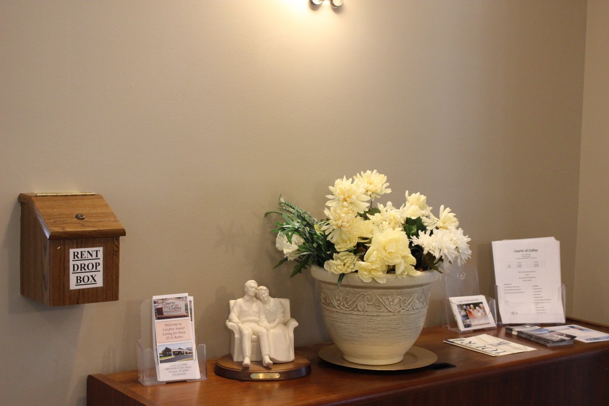 A decorative arrangement with flowers in a vase and various ornaments on a table.