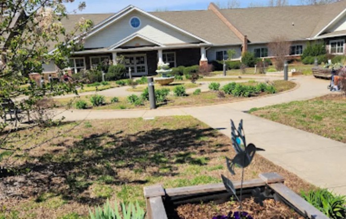 A well-maintained garden in front of a building with a pathway and decorative elements.