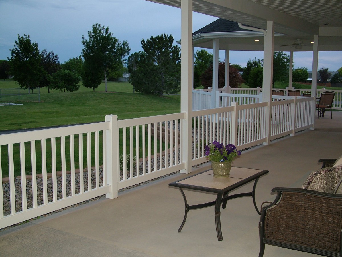 A tranquil porch setting overlooking a grassy landscape with outdoor furniture.