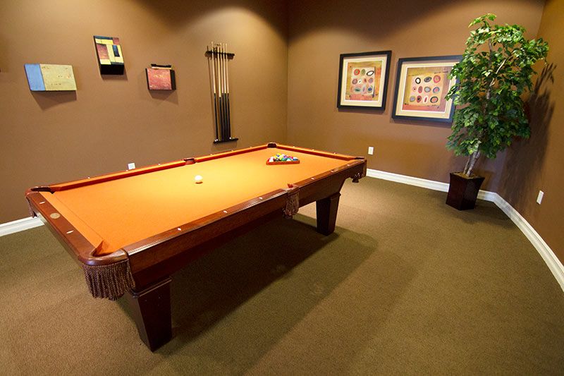 A cozy game room featuring a billiards table with a warm color scheme.