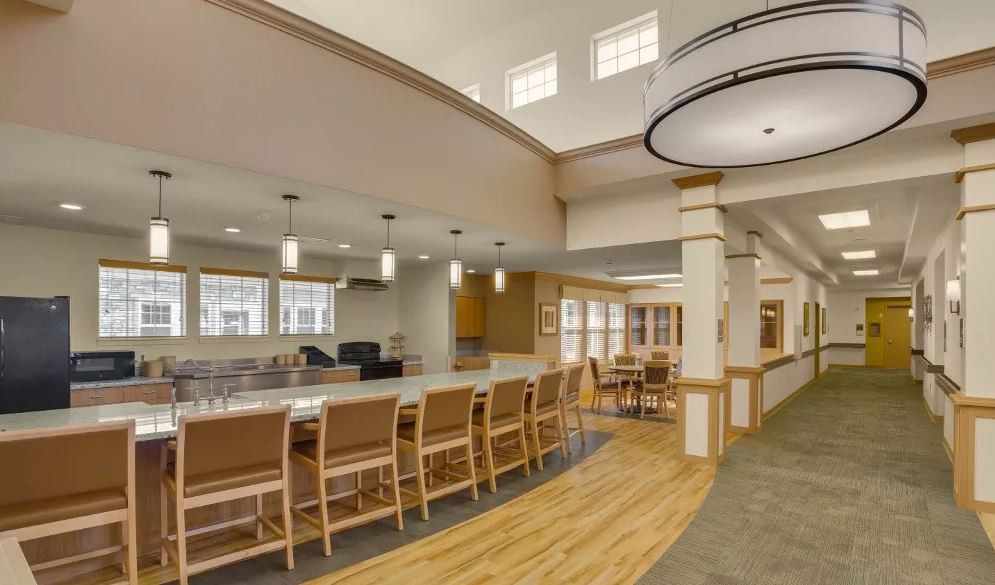 A modern community kitchen and dining area with ample seating and elegant lighting.