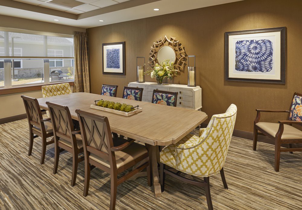A contemporary dining room with a large wooden table, stylish chairs, decorative artwork, and an elegant mirror.