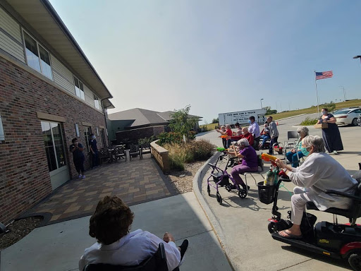 A gathering of seniors enjoying an outdoor social event, with some using wheelchairs and scooters.