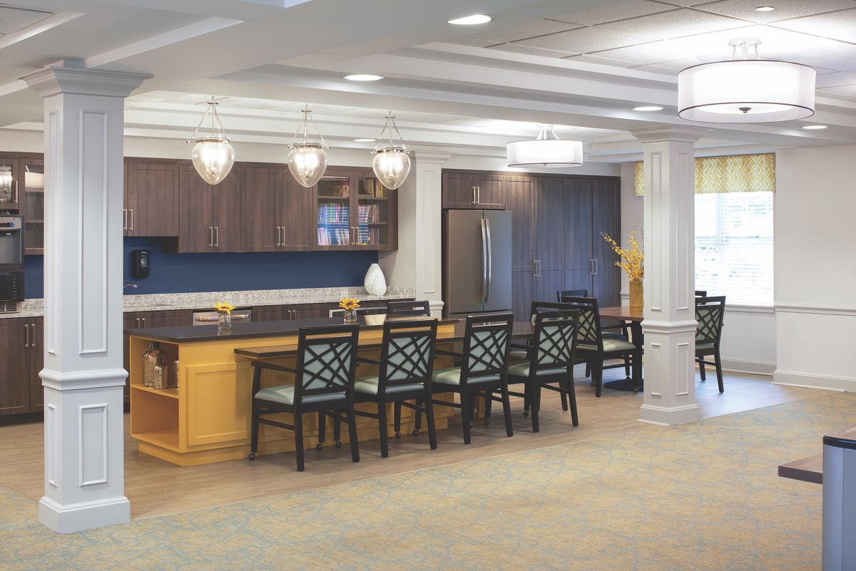 A modern kitchen interior with a seating area and elegant pendant lighting.
