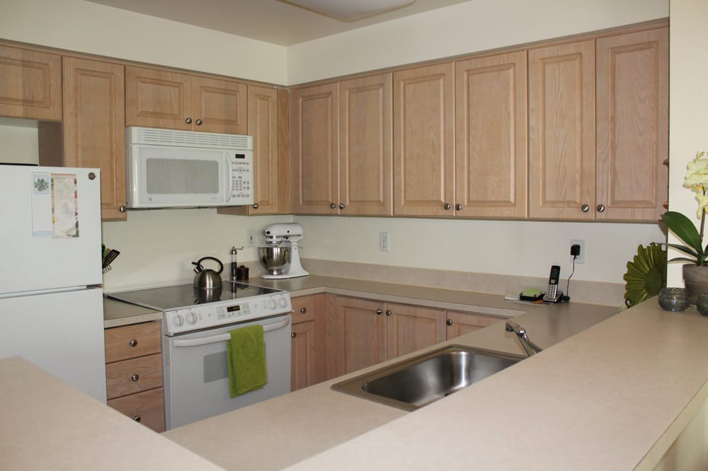 A modern kitchen with wooden cabinets, a built-in microwave, and stainless steel appliances.