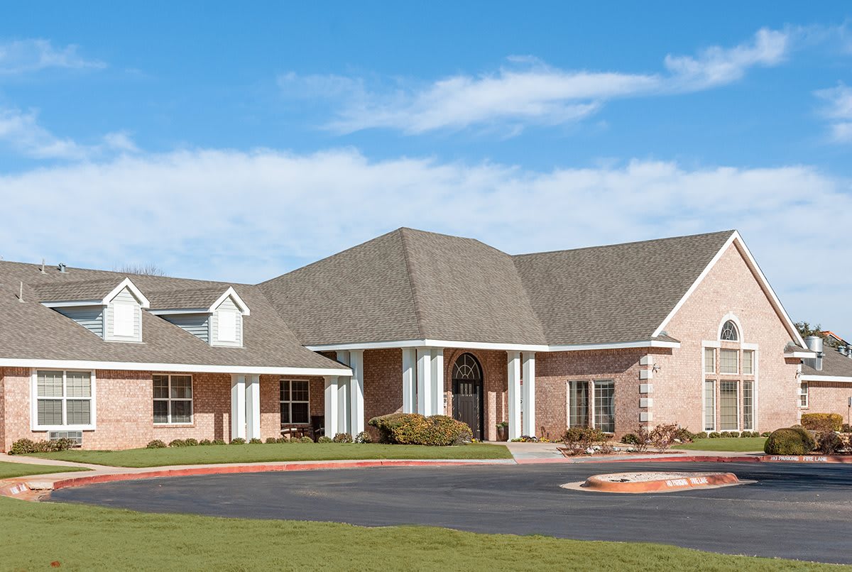 A suburban brick residential building with a driveway under a clear blue sky.