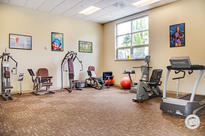 A small gym with various exercise equipment, including bikes and weights.