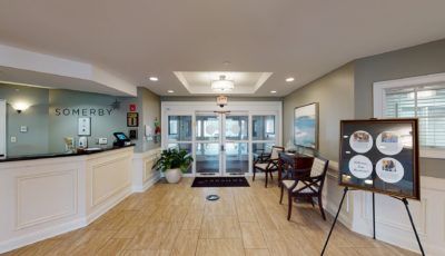 A modern lobby with a reception desk, seating area, and entrance doors.