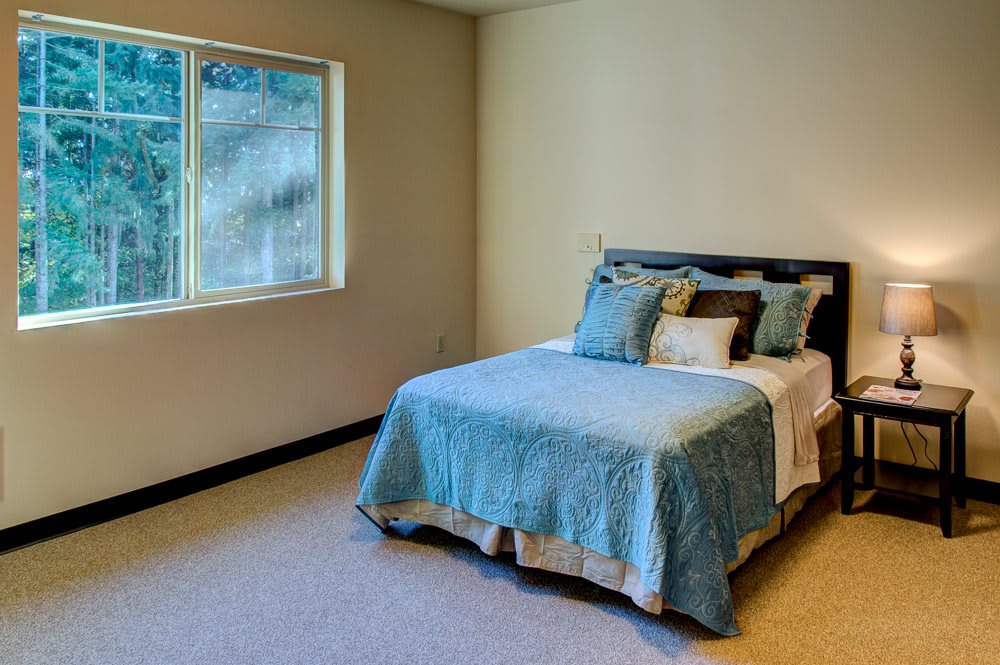 A neatly decorated bedroom with a bed and pillows next to a window.